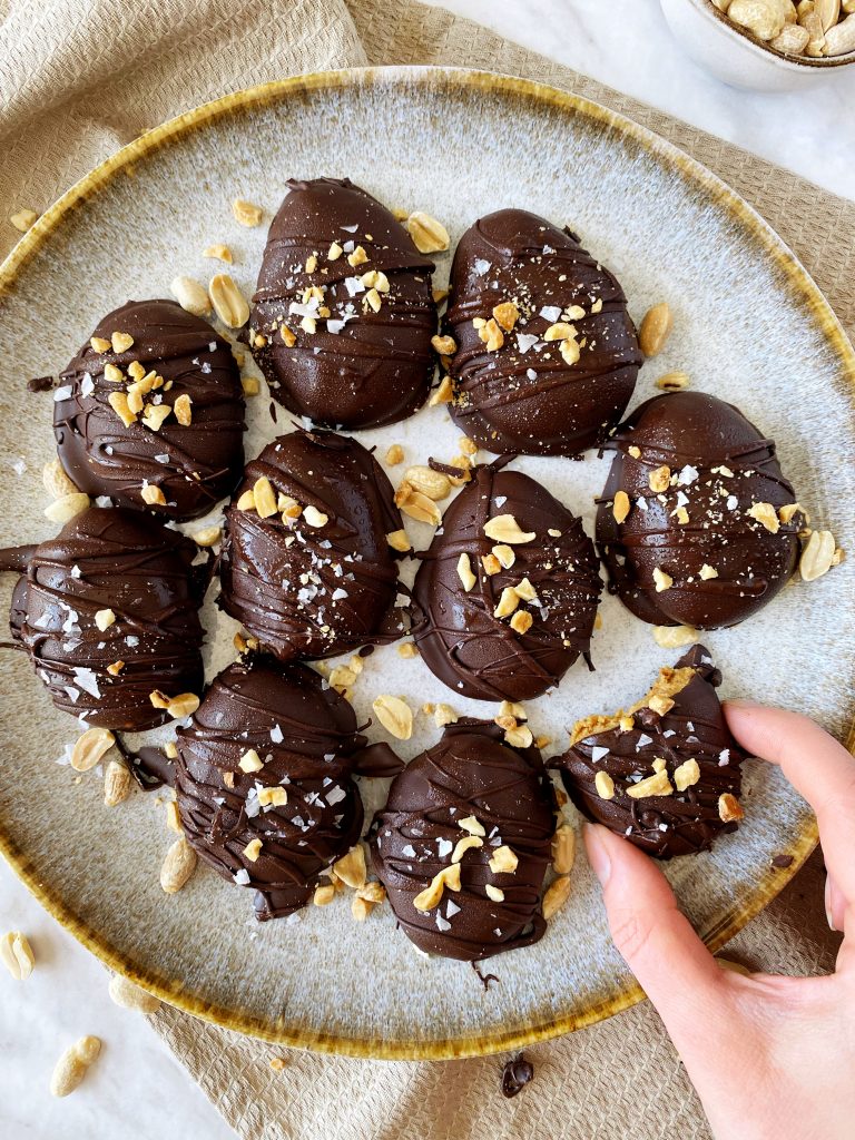 plate of reese's eggs with a hand holding an egg with a bite taken out of it