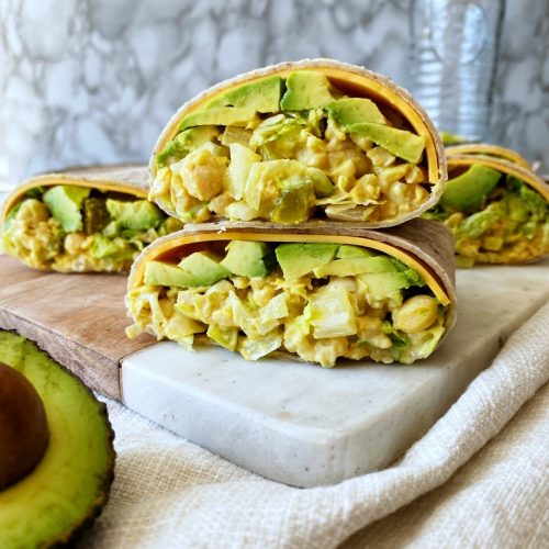 chickpea "egg" salad wraps cut in half stacked on a cutting board