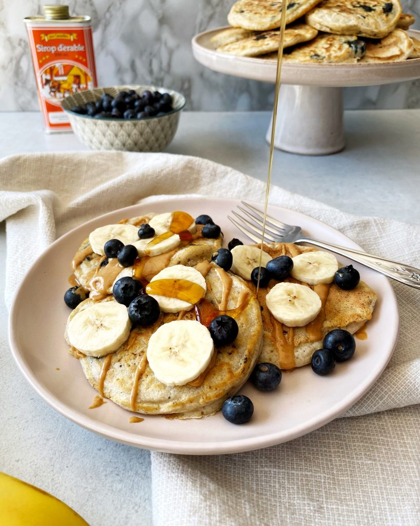 blueberry vegan pancakes being poured with maple syrup