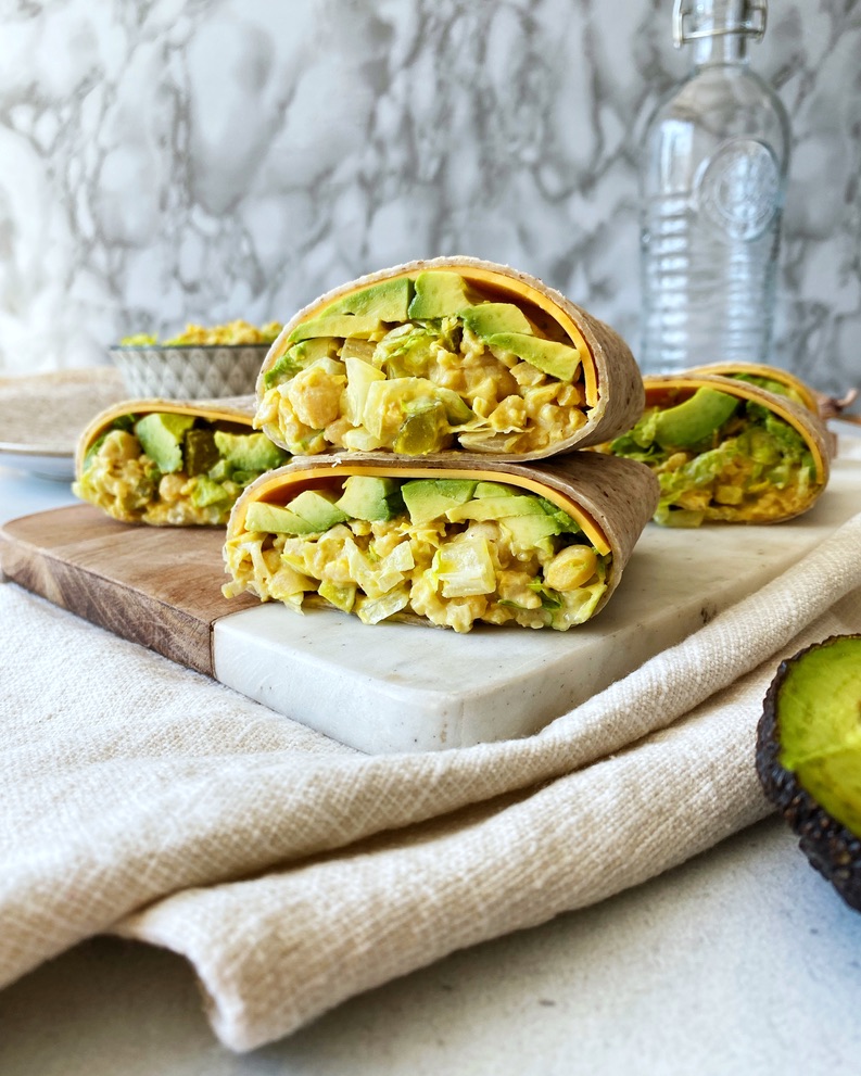 chickpea "egg" salad wrap halves stacked on top of each other on a cutting board