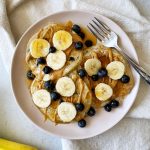 fluffy vegan blueberry pancakes topped with bananas blueberries and maple syrup