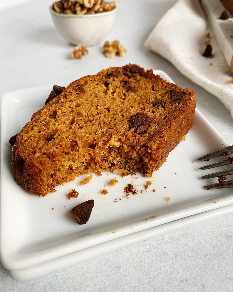 one slice of pumpkin bread in a square plate with a bite missing. 