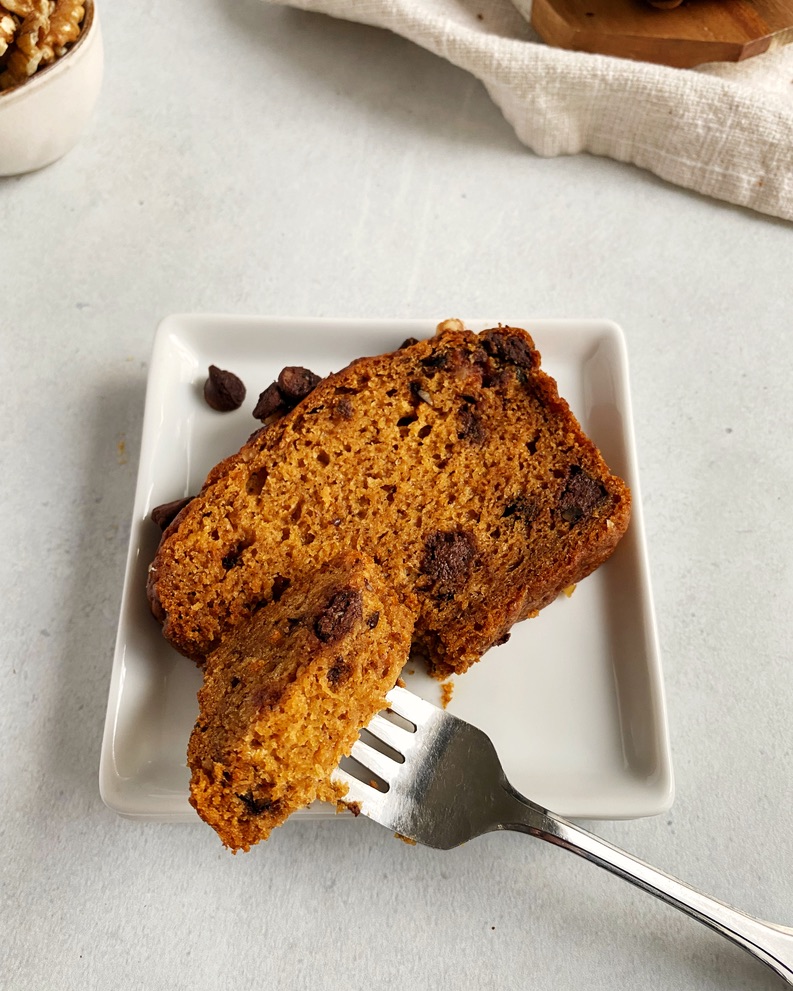 one slice of pumpkin bread in a square plate with a piece on a fork