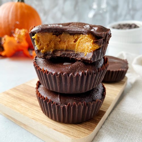 3 reese's peanut butter pumpkin cups stacked, with a bite taken out of the top cup