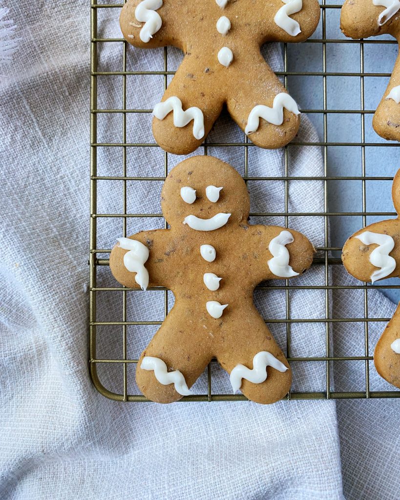 overhead closeup shot of iced gingerbread cookie on a cookie rack and tea towel on the side