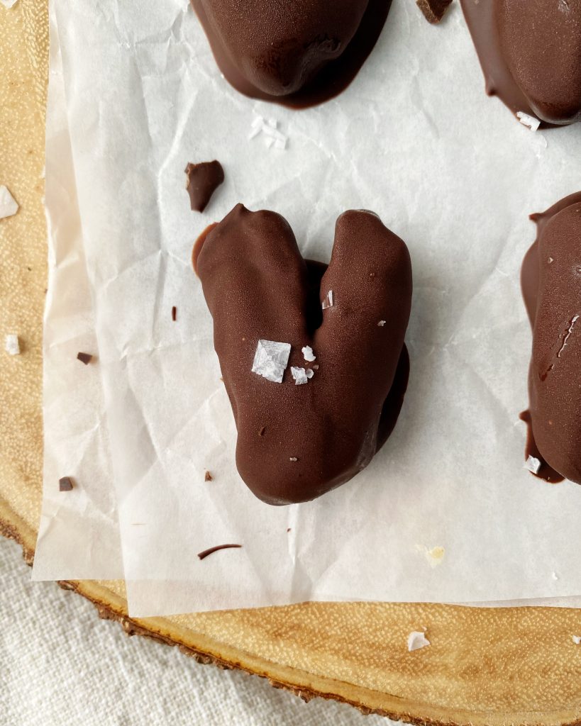 close up of chocolate covered date shaped as a heart topped with flaky salt