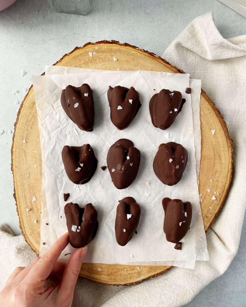 chocolate covered date hearts with hand in bottom left corner grabbing a date
