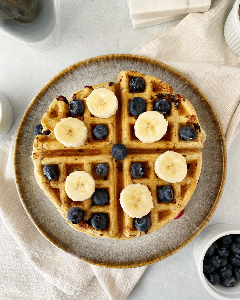 belgian waffle overhead shot on a plate topped with blueberries and sliced bananas 