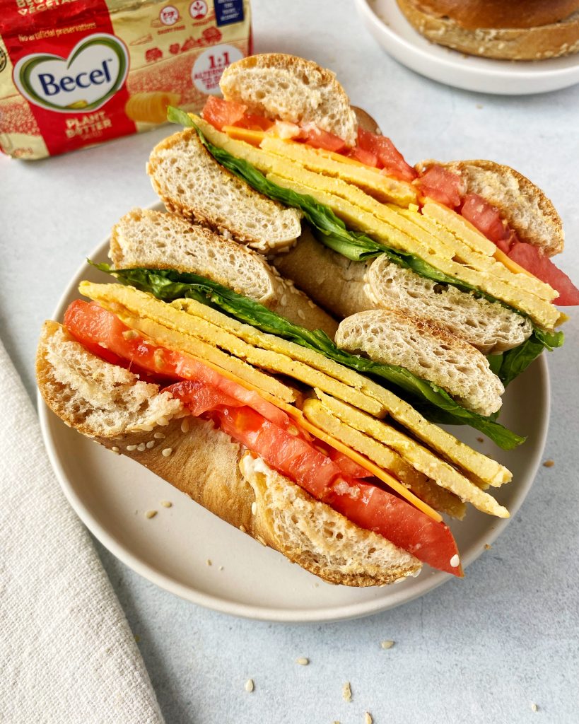 vegan breakfast bagel cut in half with cut side open on a plate