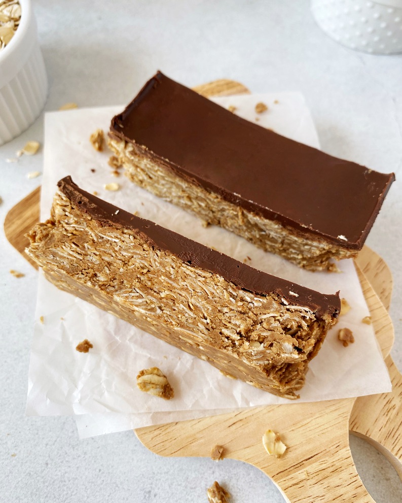 Two protein bars side by side, the closer bar turned on its side to show the oat base