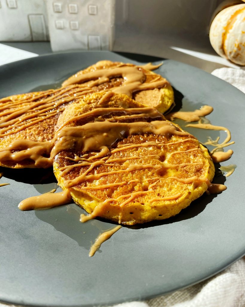 close up of pumpkin pancake with drizzle of peanut butter on top