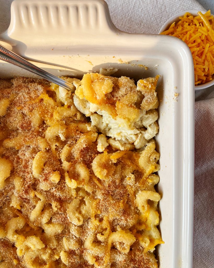 casserole dish of mac and cheese with a large spoon scooping mac and cheese