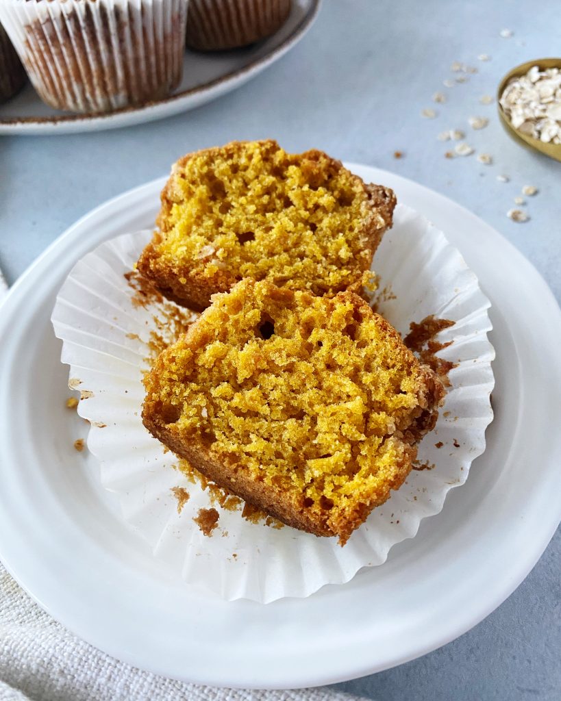 pumpkin muffin cut in half resting on muffin liner in small white plate