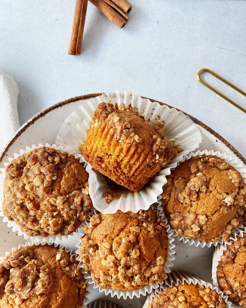 pumpkin muffins on oval serving tray with one muffin removed from liner and placed on it's side