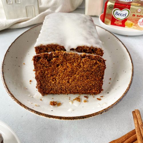 vegan gingerbread loaf on serving tray with one cut piece laying in front of the loaf