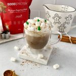gingerbread latte topped with whipped cream and marshmallows on a square marble coaster