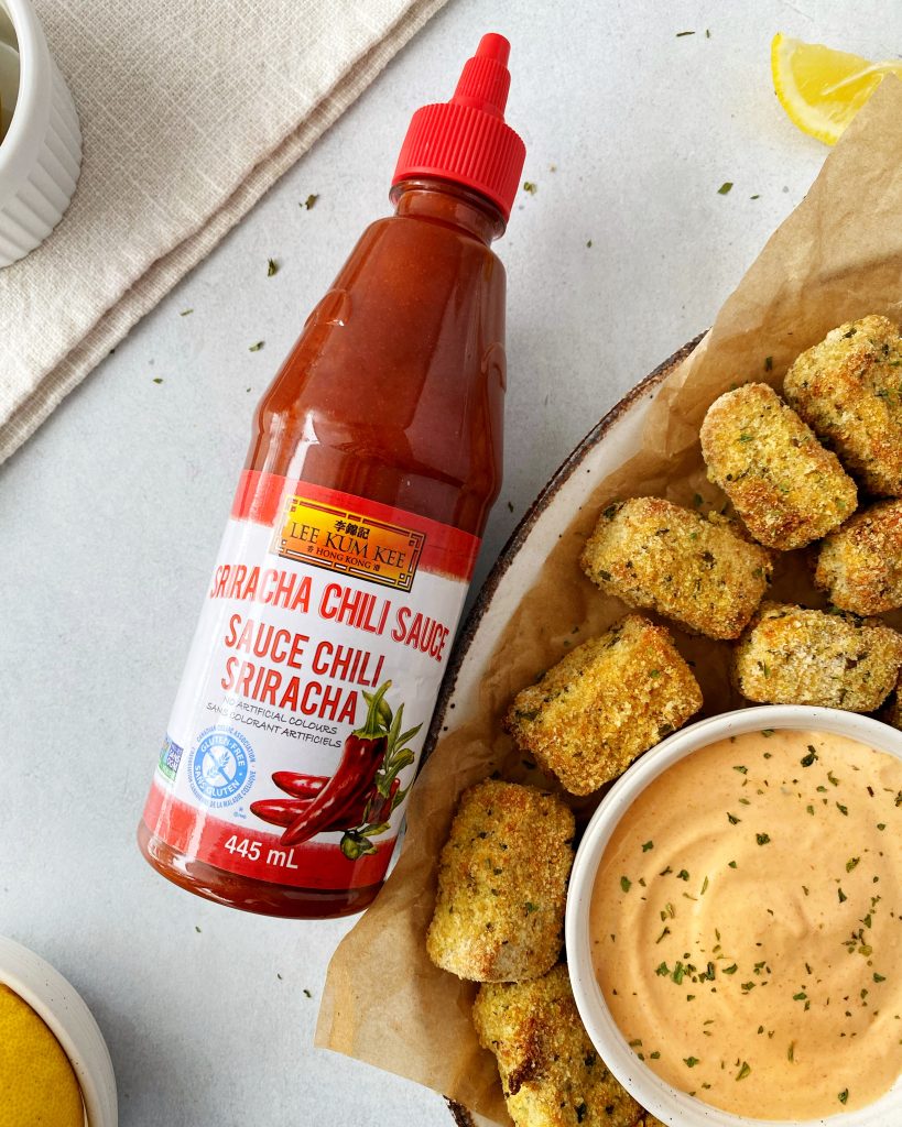 tofu bites with dipping sauce in a serving tray with lee kum kee sriracha bottle on the left