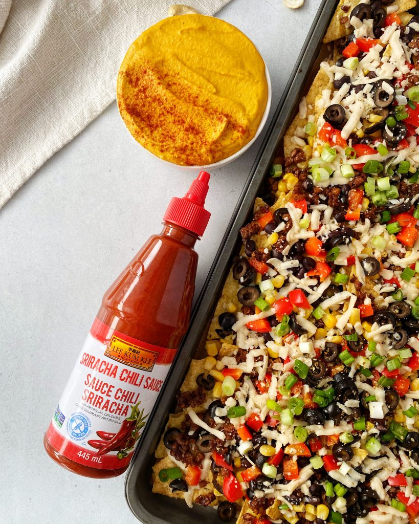 vegan nachos with Lee Kum Kee Sriracha Chili sauce bottle next to tray