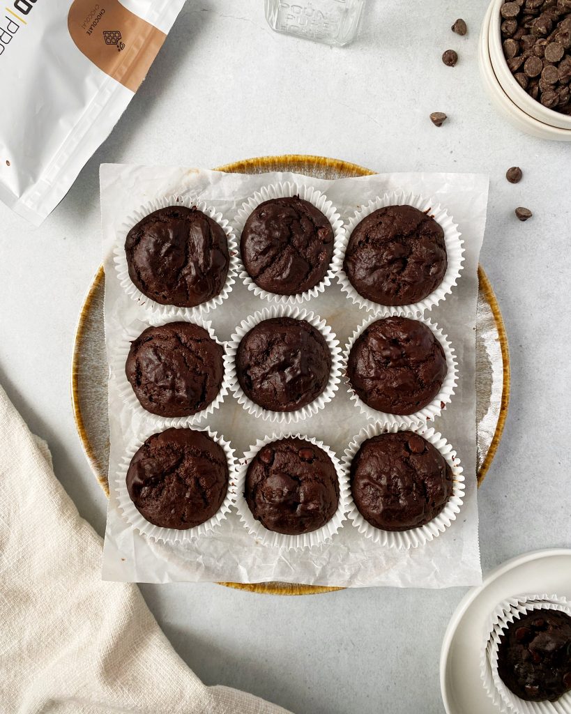 vegan chocolate protein muffins on a round plate lined with parchment paper