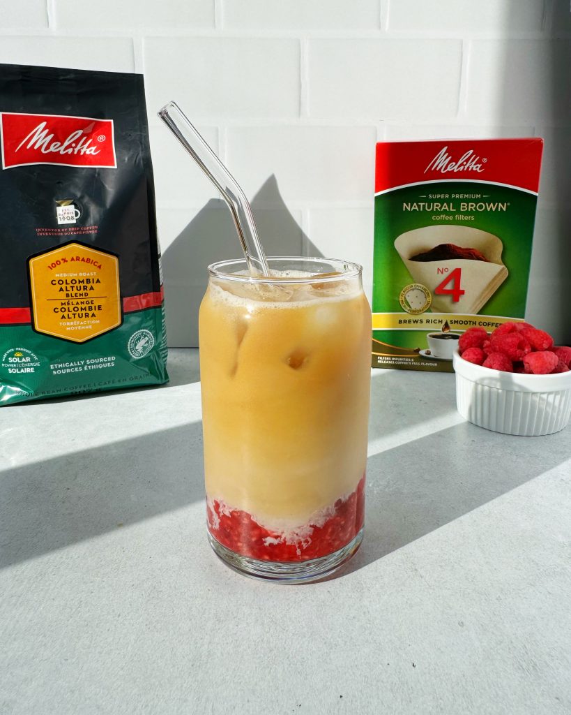 raspberry iced latte in glass mug with glass straw