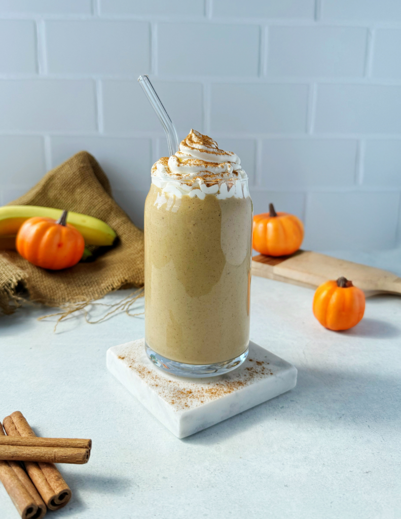 high protein pumpkin spice smoothie topped with whipped cream and cinnamon