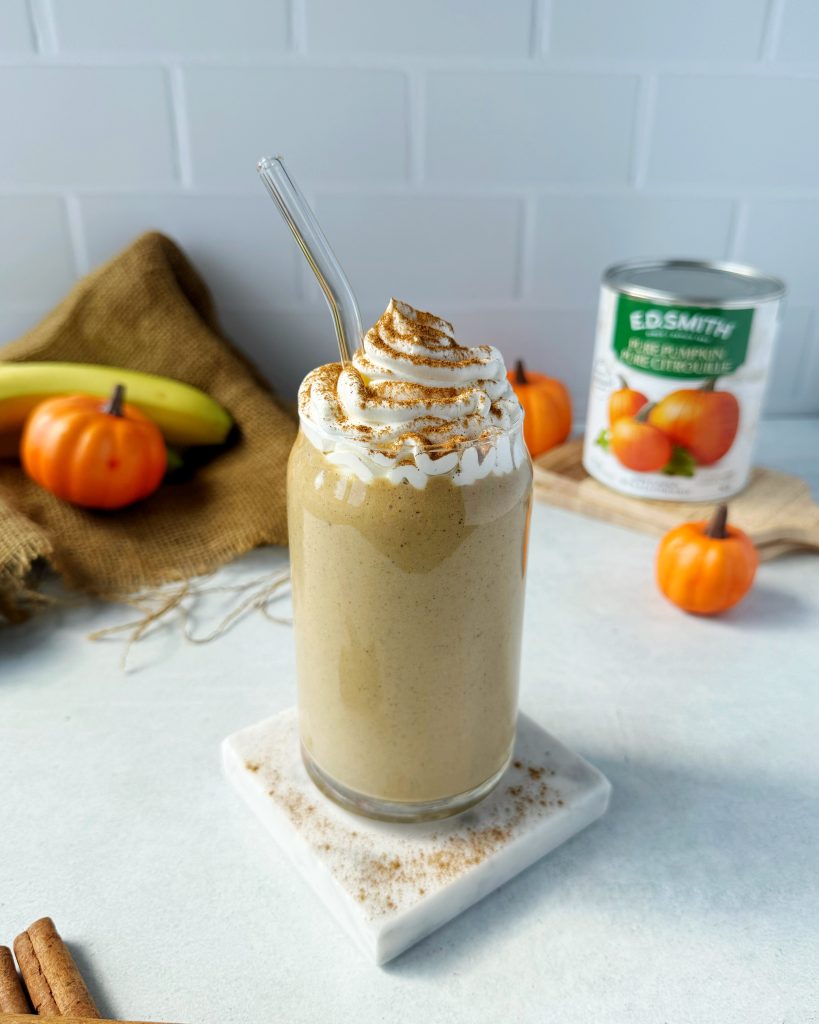 high protein pumpkin spice smoothie topped with whipped cream and cinnamon