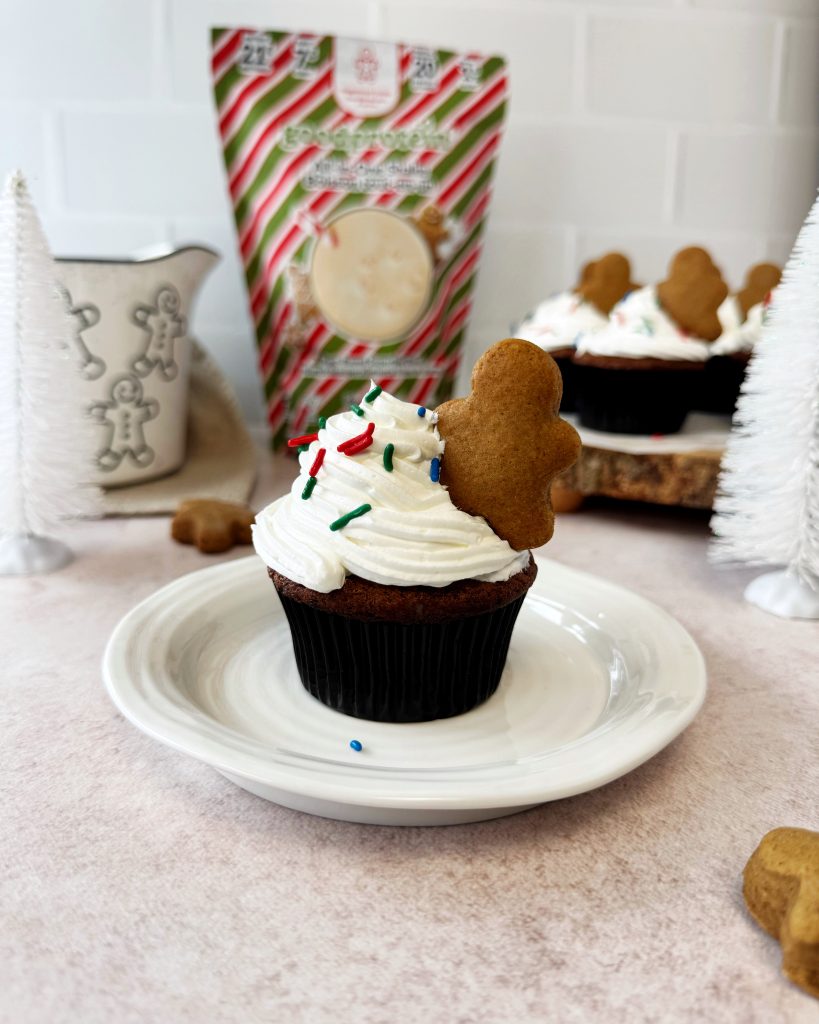 high protein gingerbread muffins with frosting and a mini gingerbread cookie placed in the frosting