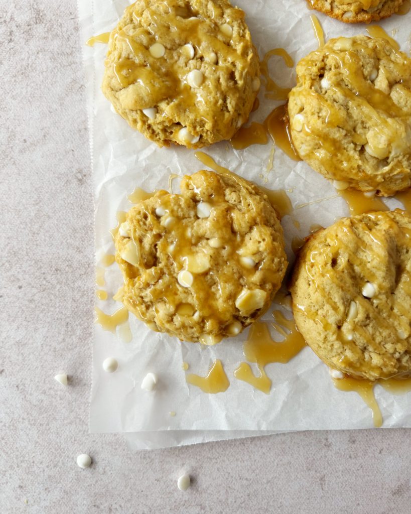 vegan salted caramel cookies on a white parchment paper with caramel drizzle