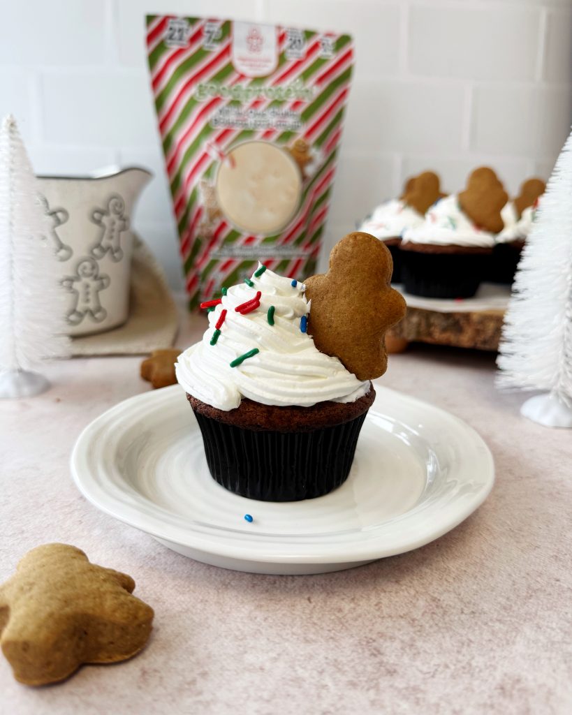 gingerbread muffins on a white plate with frosting and a mini gingerbread stuffed into the frosting