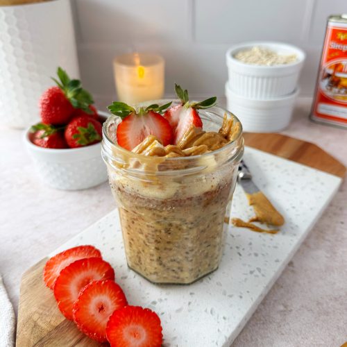 overnight oats in glass jar topped with strawberries, banana, and peanut butter