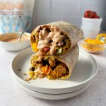 ultimate vegan burritos stacked on top of each other drizzled with sauce