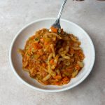 lentil bolognese with fork in round speckled bowl