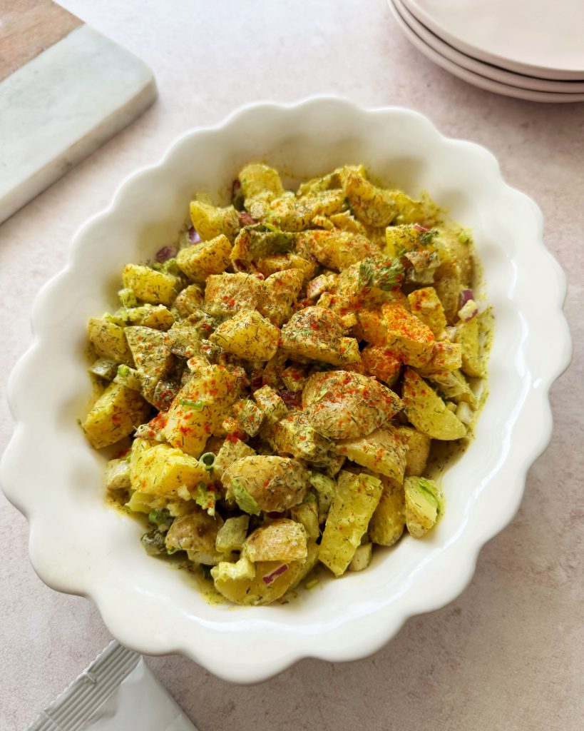 Vegan potato salad in white scalloped edge oval bowl