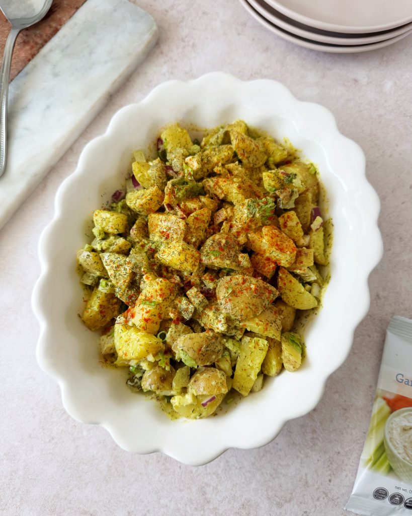 vegan potato salad topped with dill and paprika in oval bowl